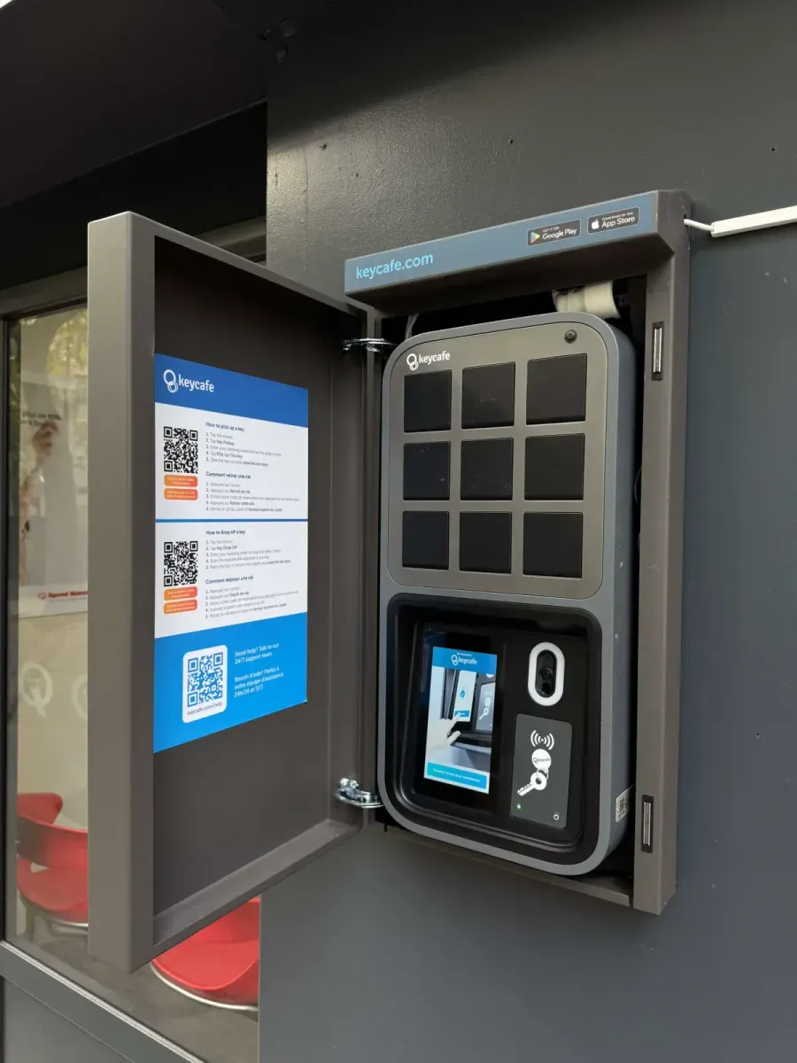 Caja de llaves Keycafé abierta en la fachada exterior de la lavandería, nueve casilleros y lector contactless, accesible las veinticuatro horas