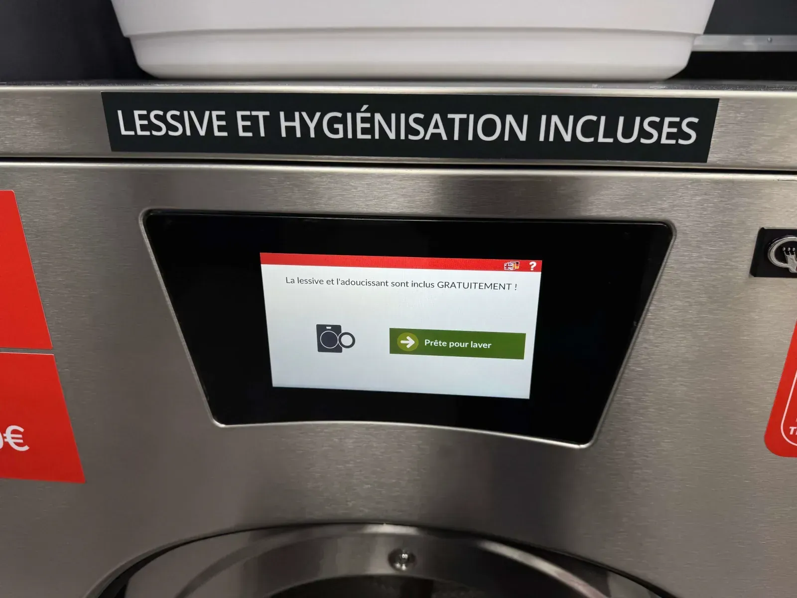 Bandeau d'une machine portant la mention « Lessive et hygiénisation incluses » et écran annonçant que la lessive et l'adoucissant sont inclus gratuitement