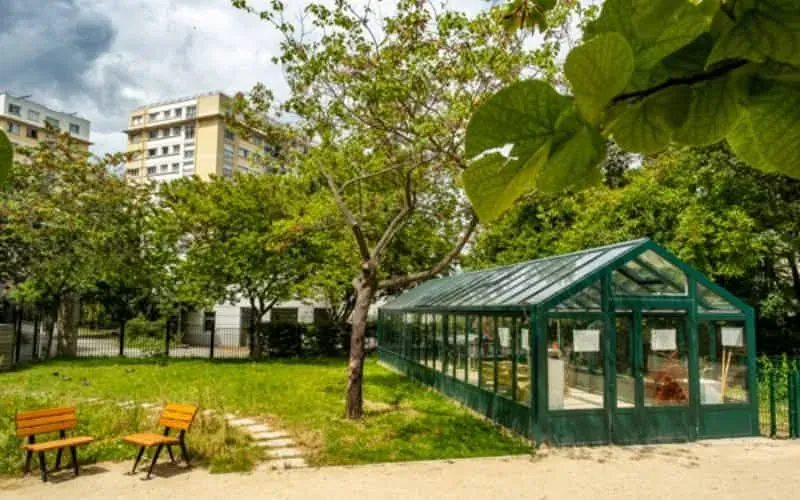 The teaching greenhouse and benches under the trees of Square Paul Paray, Paris 17th
