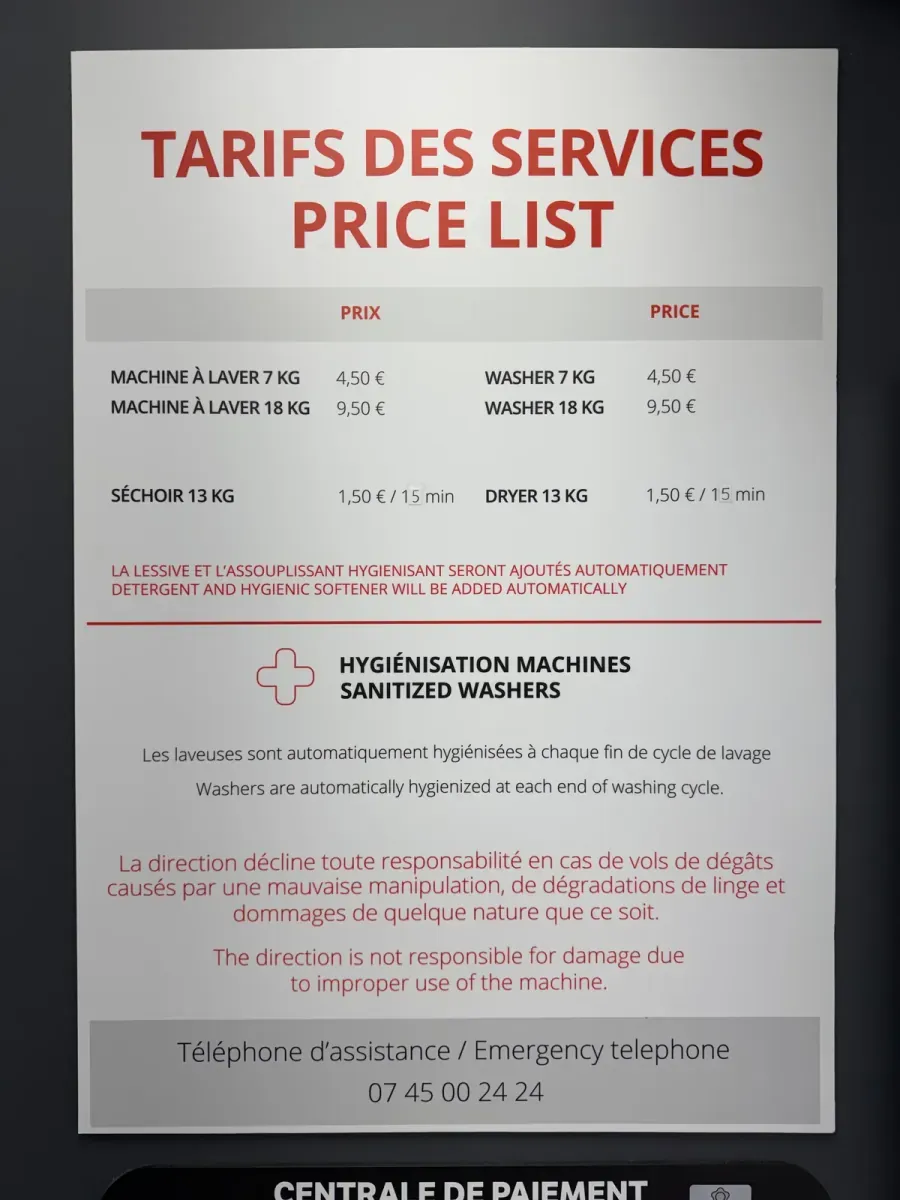 The price board in the launderette: 7 kg wash €4.50, 18 kg wash €9.50, drying €1.50, detergent and softener added automatically